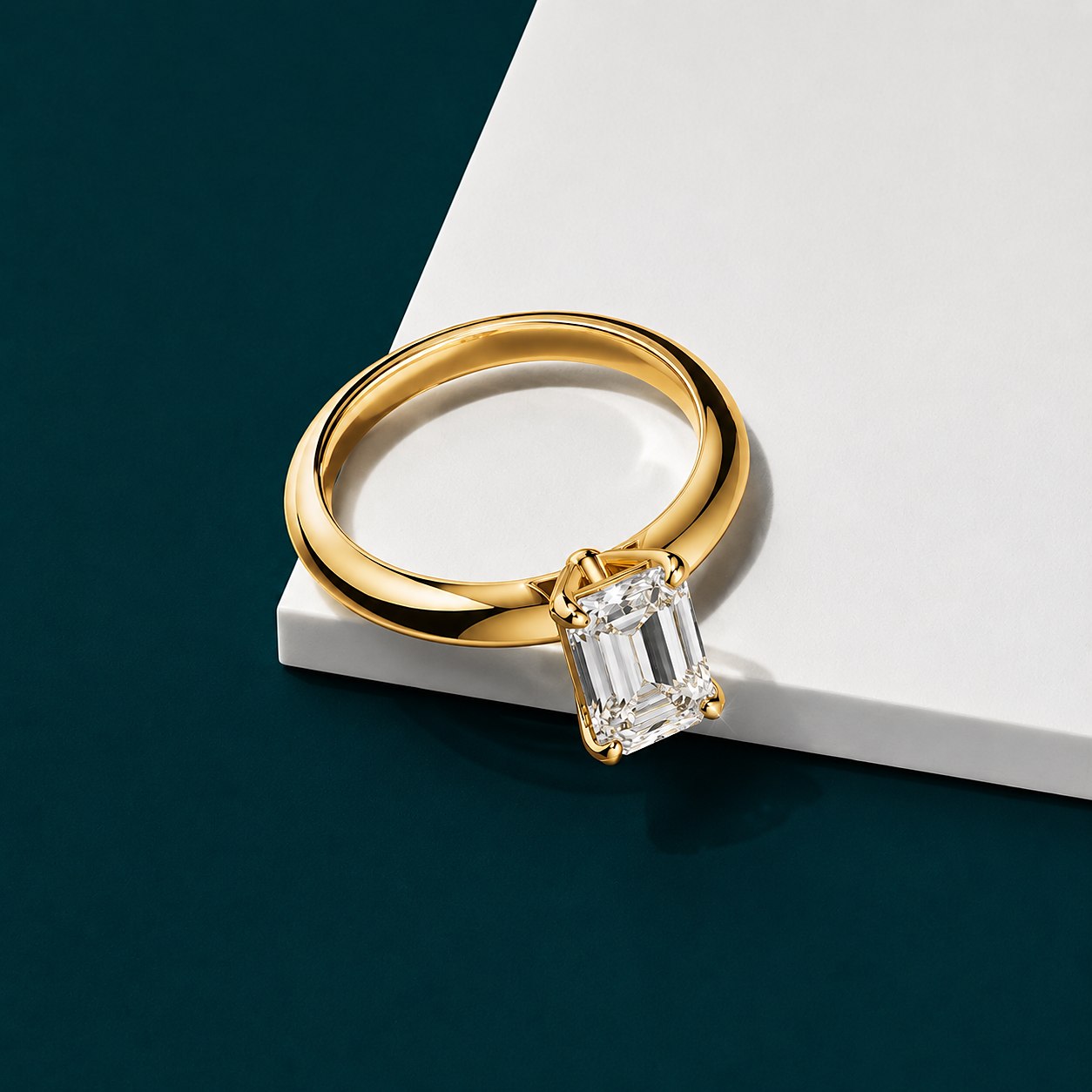 Emerald-cut solitaire in gold on petrol